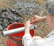 A scientist extracting a riverbank sample from a sampling device.